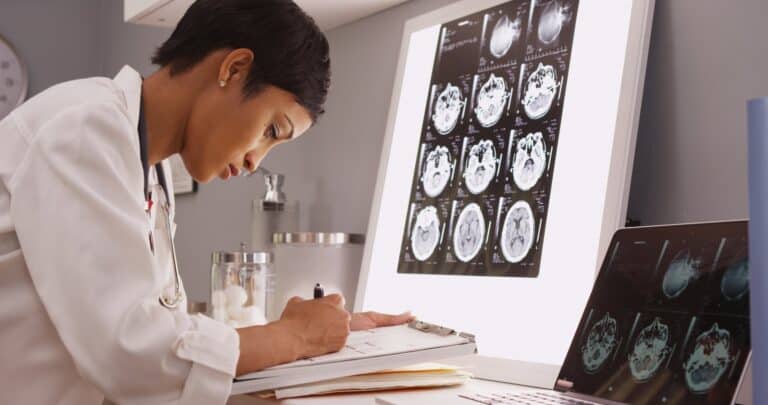 caribbean latina doctor doing research on erb's palsy looking at x-ray scans of brains and writing research results