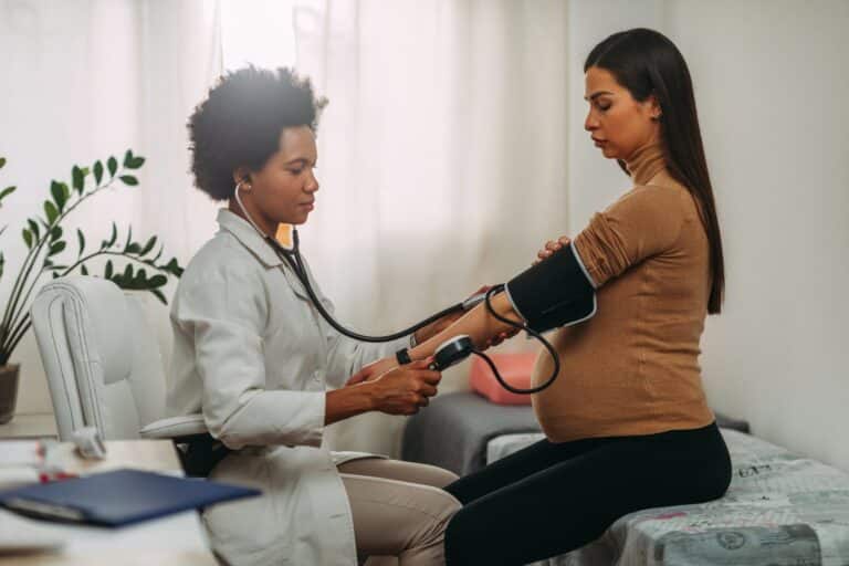 caribbean Doctor measuring blood pressure of pregnant latin american woman